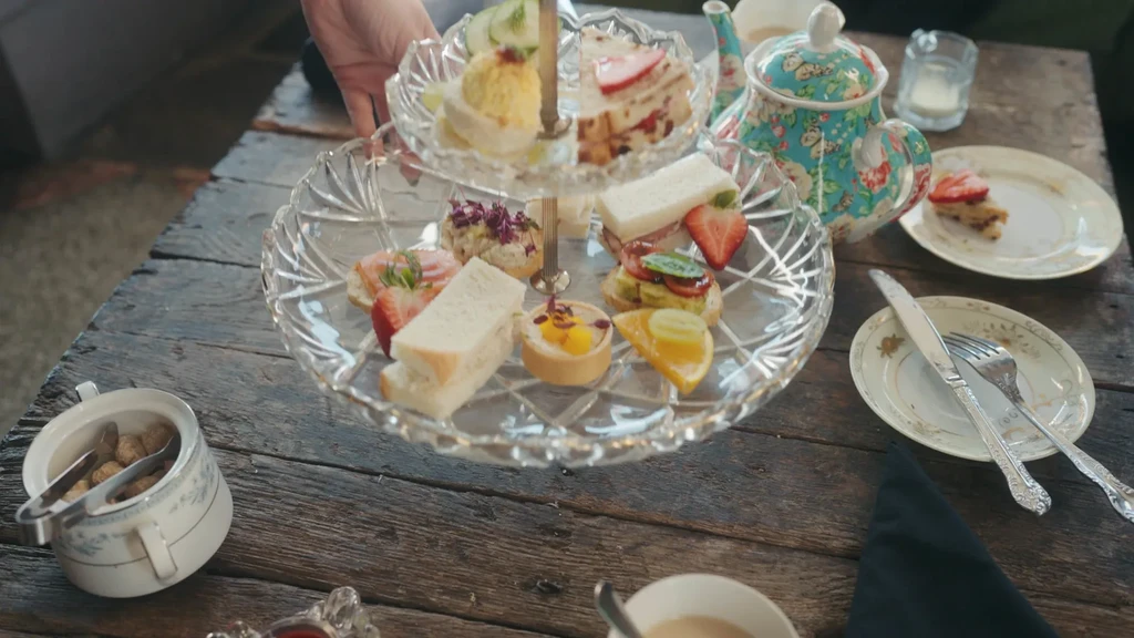 Close-up of elegant afternoon tea with tiered stand of small foods.