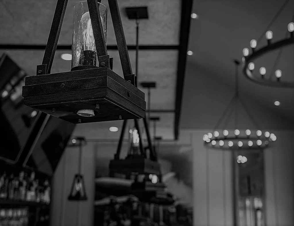 B&W photo: detailed wooden and metal pendant light with Edison bulb.