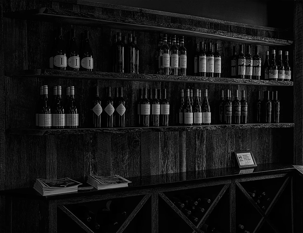 Black and white rustic wooden wine display filled with bottles.