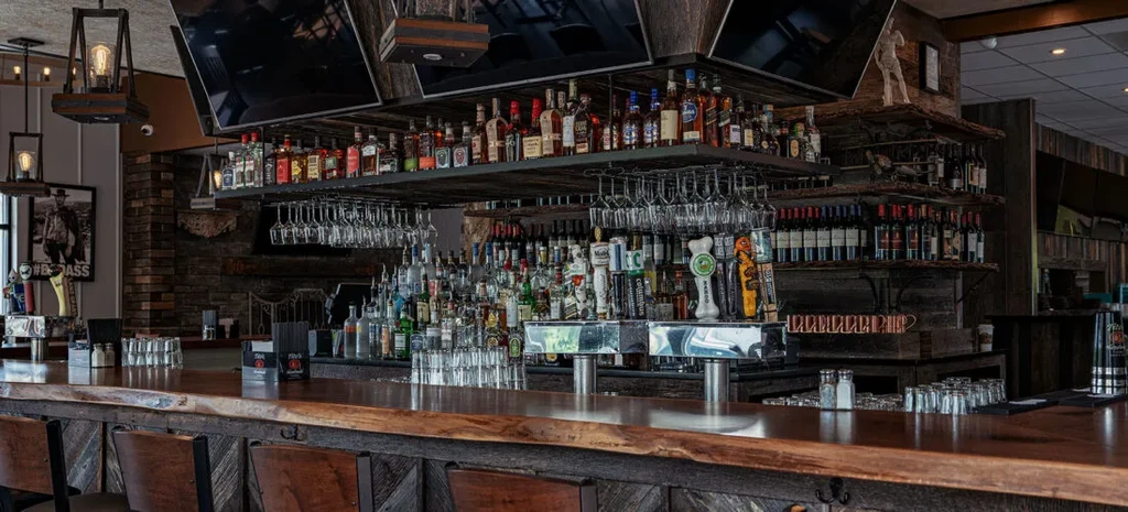 Rustic bar with live-edge wood counter, liquor bottles, and beer taps.