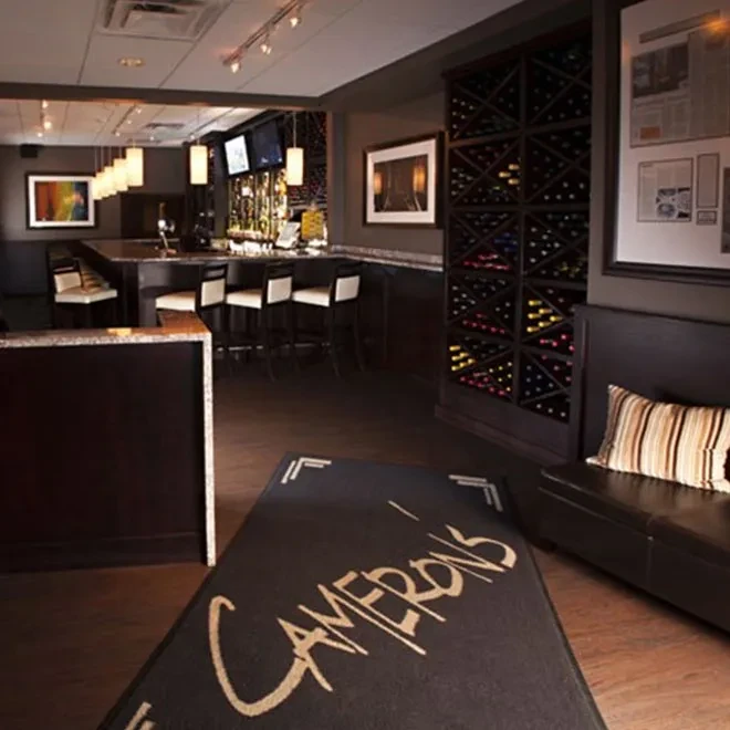 Empty restaurant bar with wine rack and 'CAMERON'S' floor mat.