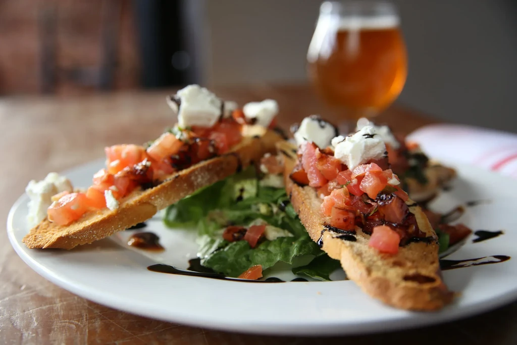 Two bruschetta with tomatoes, white cheese, herbs, balsamic glaze.