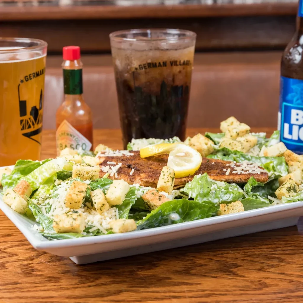 Caesar salad with grilled fish or chicken, lemon, and assorted drinks.
