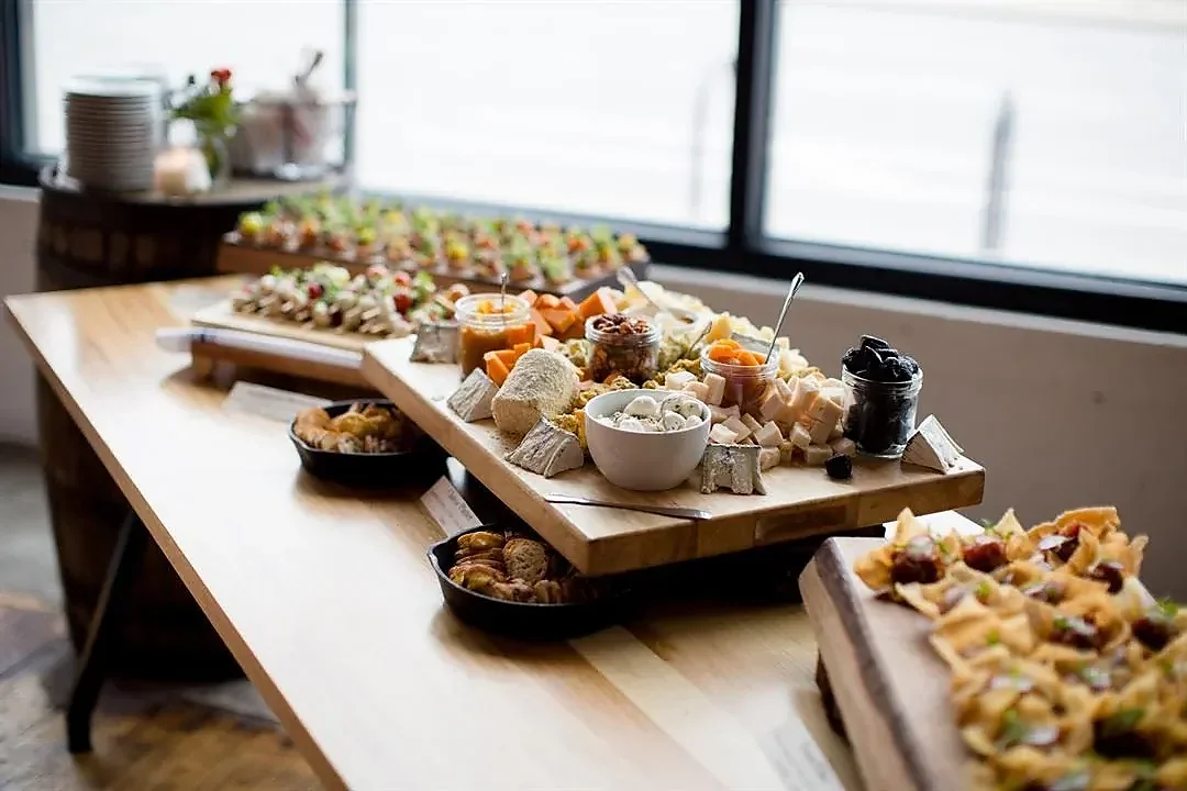 Cheese board and appetizer trays on wooden table by windows