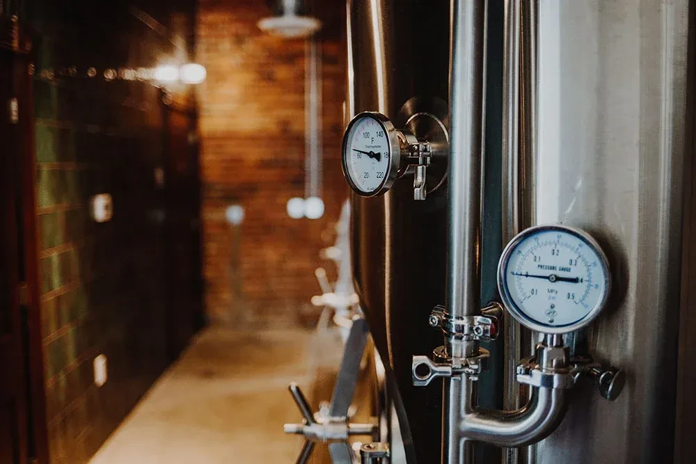 Stainless steel fermentation tanks showing temperature and pressure gauges.