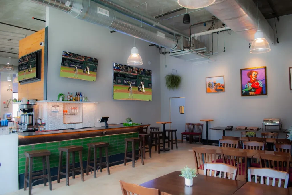 Empty modern bar and dining room with baseball on TV.