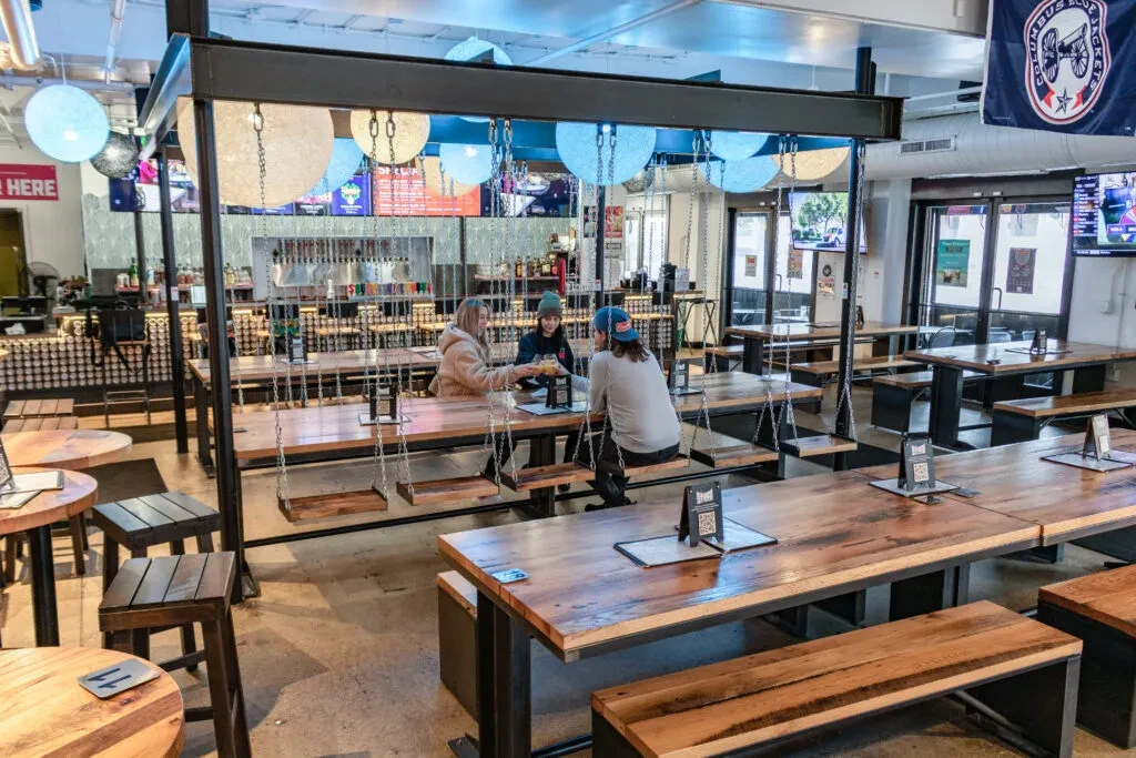 Modern industrial restaurant interior with unique wooden swing seats.