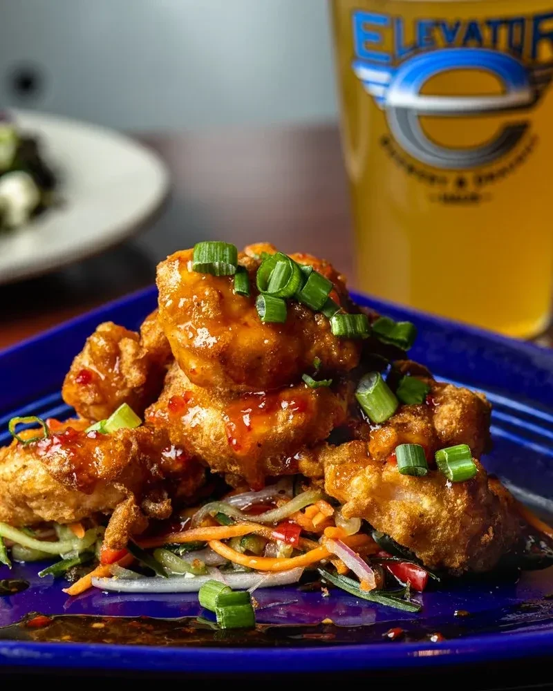 Golden-brown fried chicken with red sauce and slaw on blue plate.