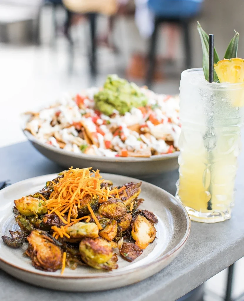 Close-up: roasted Brussels sprouts, tropical cocktail, and nachos.
