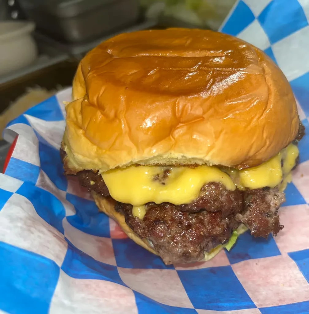 Double cheeseburger with two patties, melted cheese, lettuce, checkered liner.