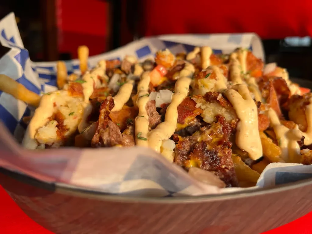 Loaded fries with crispy meat, creamy sauce, and green herbs.