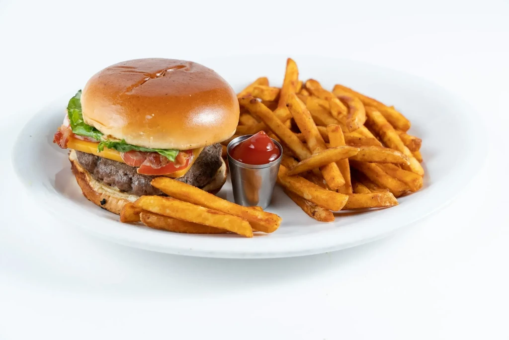 Studio photo of a classic hamburger, fries, and ketchup on white plate.