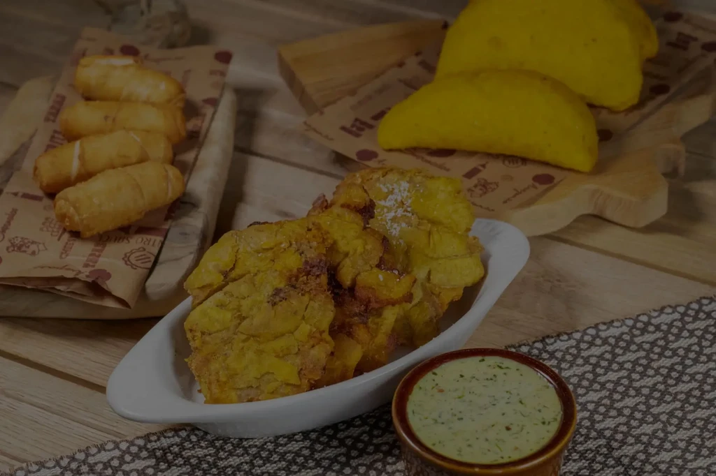 Fried plantains, cheese sticks, and empanadas on a rustic table.