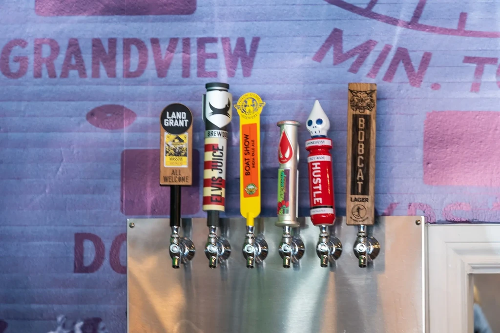 Six distinct beer tap handles with various brands on display.
