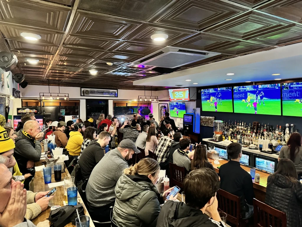 Bustling sports bar with patrons watching a game on multiple TVs.