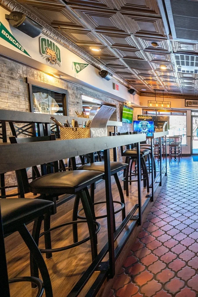 Empty sports bar with high-top table, brick walls, and sports TVs.