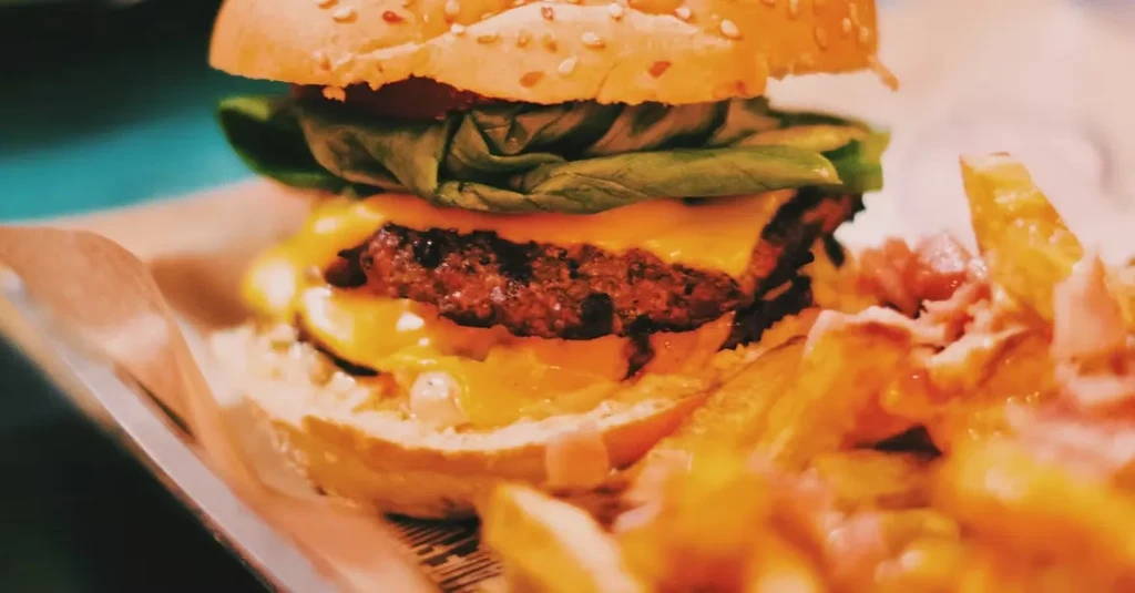 Close-up of double patty cheeseburger and side of loaded fries.