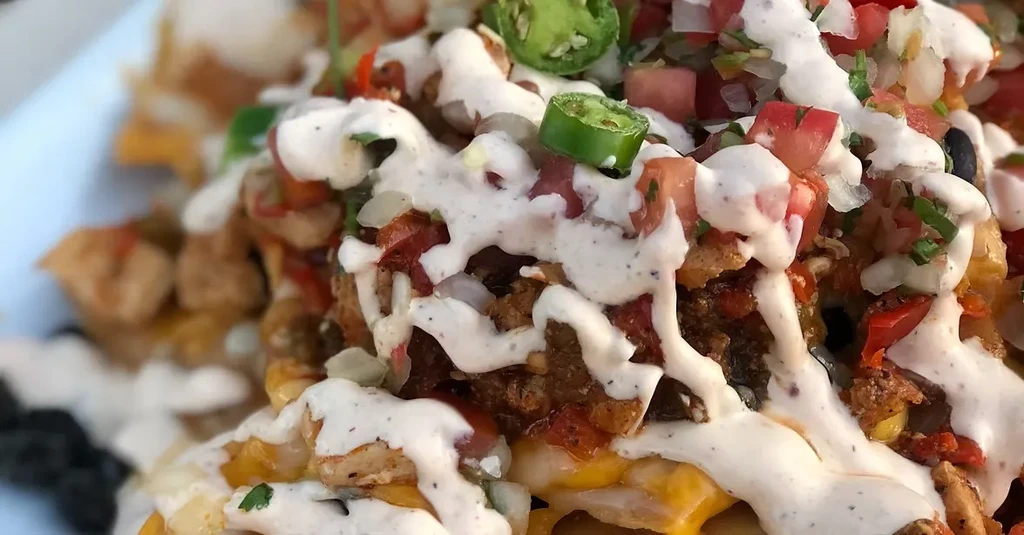 Loaded nachos with melted cheese, chicken, jalapeños, and creamy sauce.