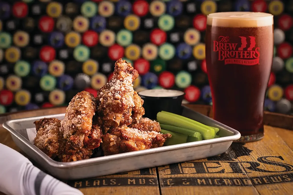 Parmesan wings on metal tray with celery and pint of beer