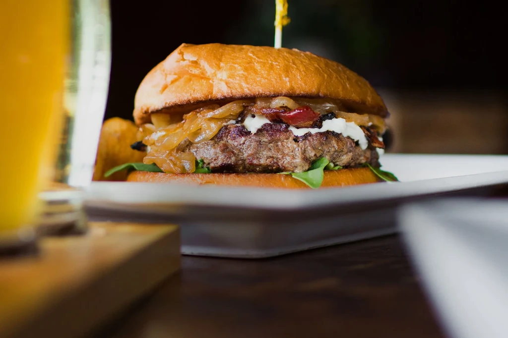 Gourmet burger with beef, bacon, cheese, onions, lettuce, brioche bun.