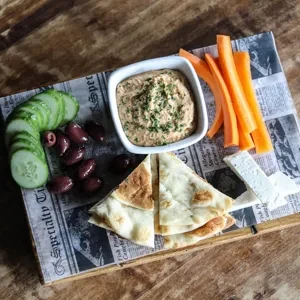Mezze platter with hummus, vegetables, cheese, olives, and pita.