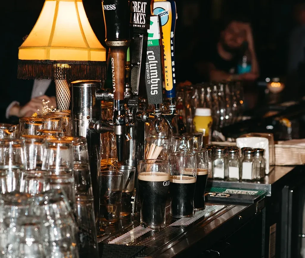Bar counter with prominent beer taps including Guinness and filled glasses.