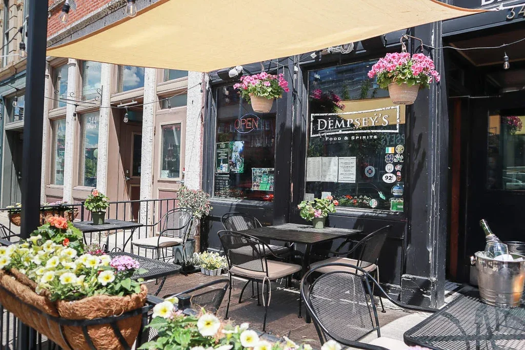 Dempsey's Food & Spirits exterior with sunny patio, tables, and flowers.