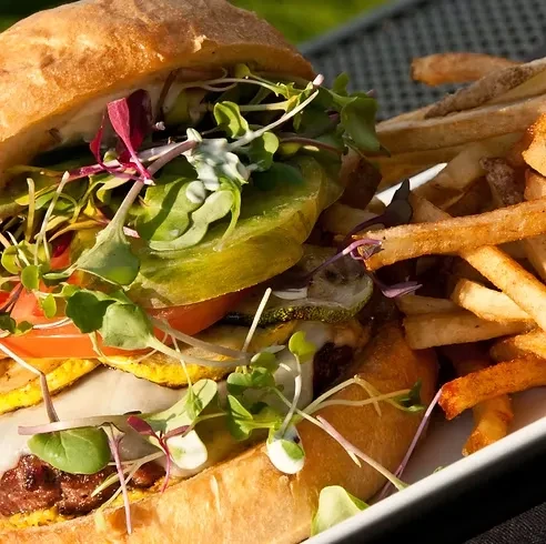 Gourmet sandwich or burger with crispy fries on a white plate.