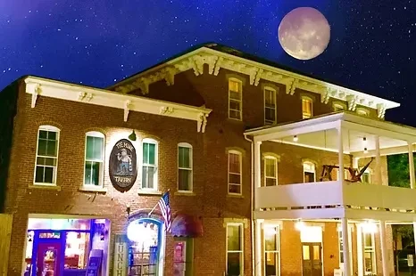 Historic brick tavern building, 'THE HOBE TAVERN', under a starry night.