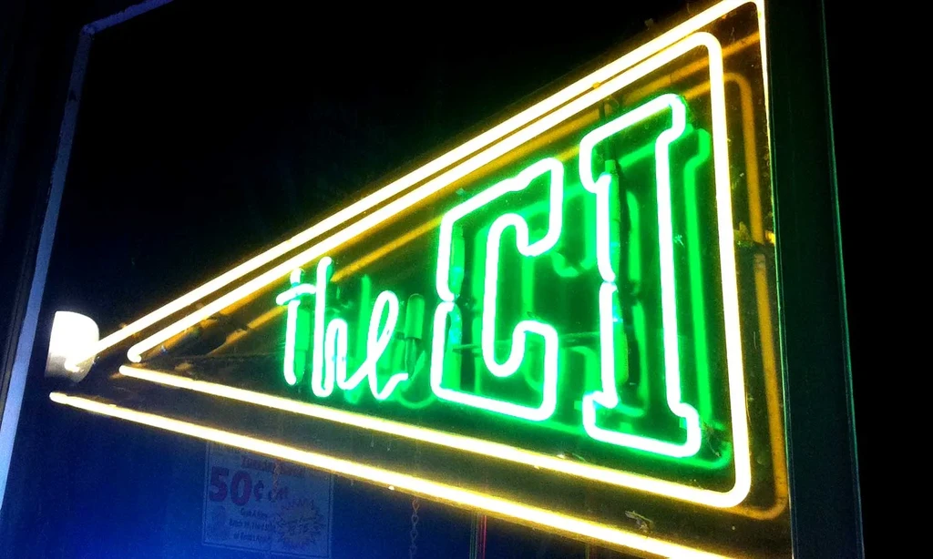 Green and yellow neon sign 'the CI', with '50¢' partially visible.
