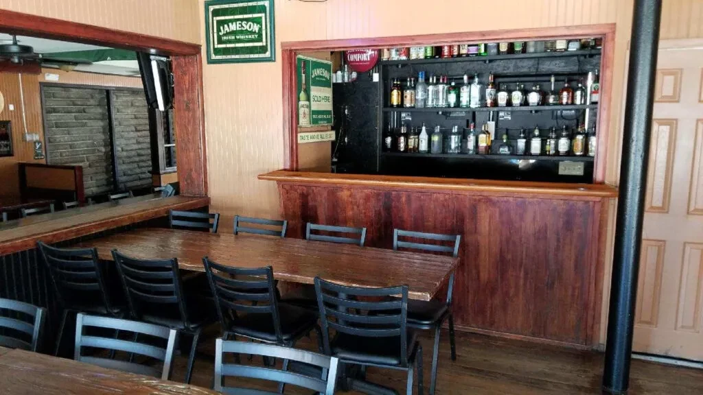 Rustic bar interior with dark wood, liquor bottles, and Jameson signs.