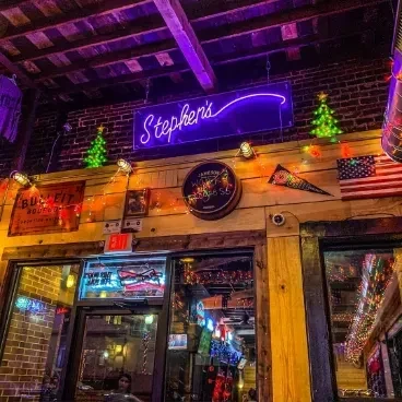 Stephen's bar interior with purple neon sign, Christmas trees, and flags.