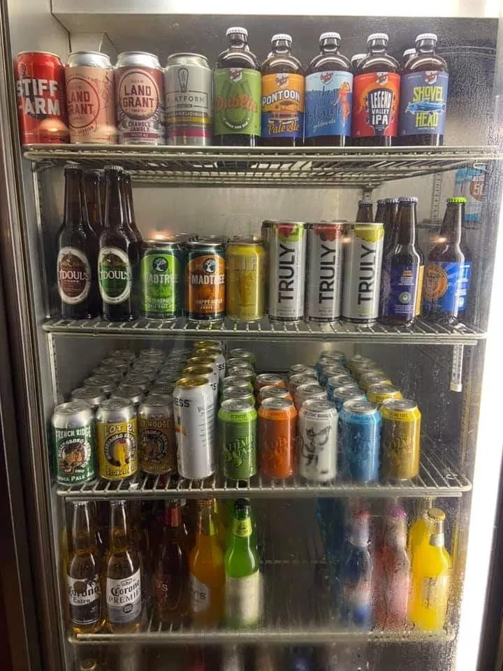 Glass-door cooler fully stocked with various canned and bottled beverages.