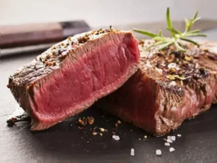 Sliced medium-rare steak, seared crust, black pepper, sea salt, rosemary garnish.