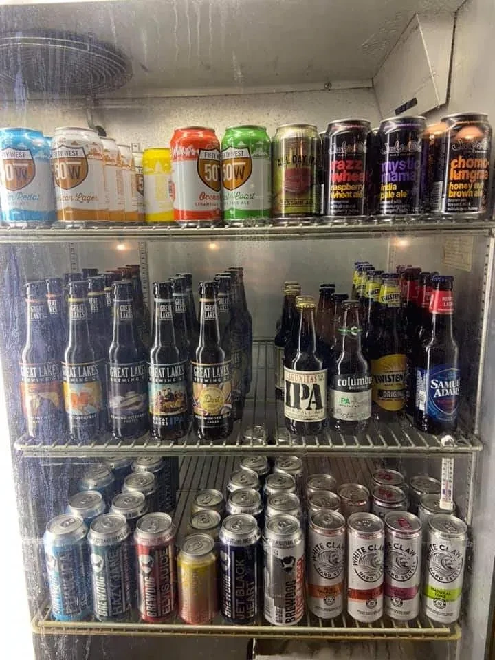 Commercial refrigerated cooler filled with assorted beer cans, bottles, and seltzers.