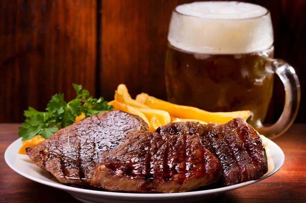 Grilled steak, golden fries, fresh parsley, and amber beer.
