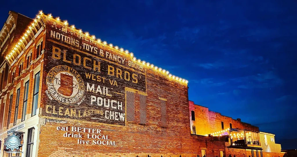 Faded 'Mail Pouch' ghost sign on old brick building at night.