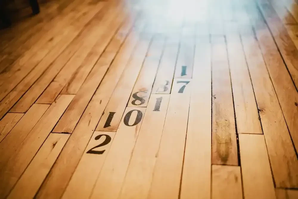 Light brown wooden floor planks with dark stenciled game numbers.