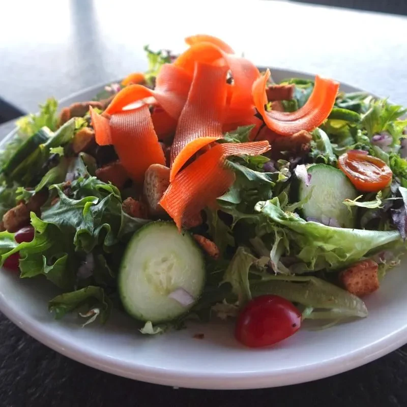 Fresh garden salad with orange carrot ribbons and cherry tomatoes.