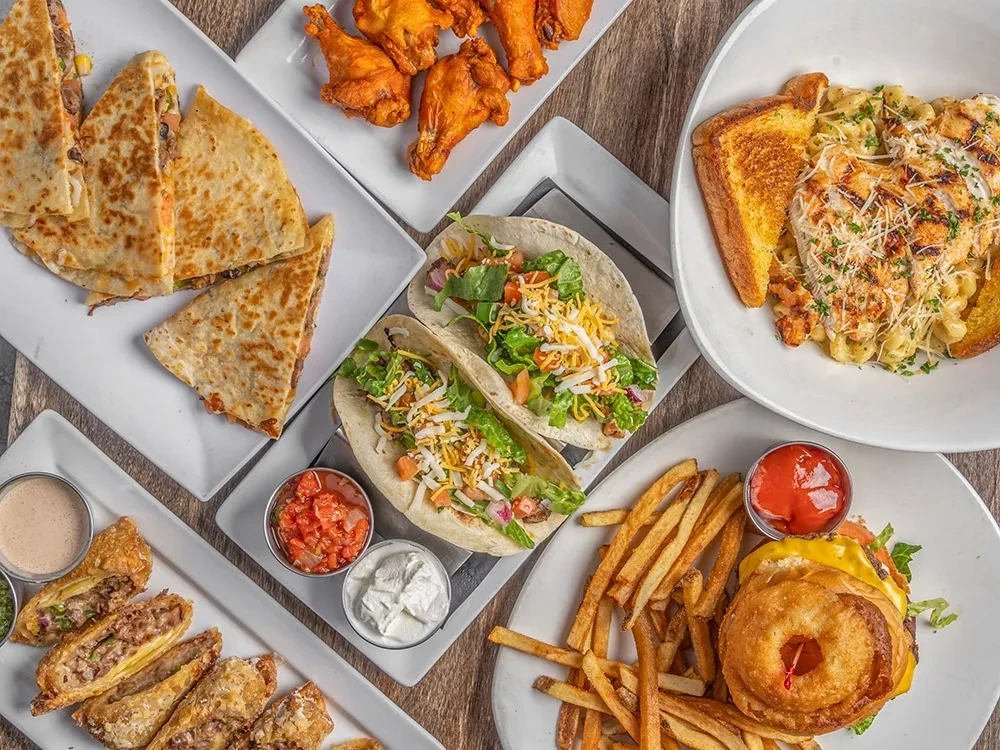 Flat lay of a diverse spread of cooked dishes on a wooden table.