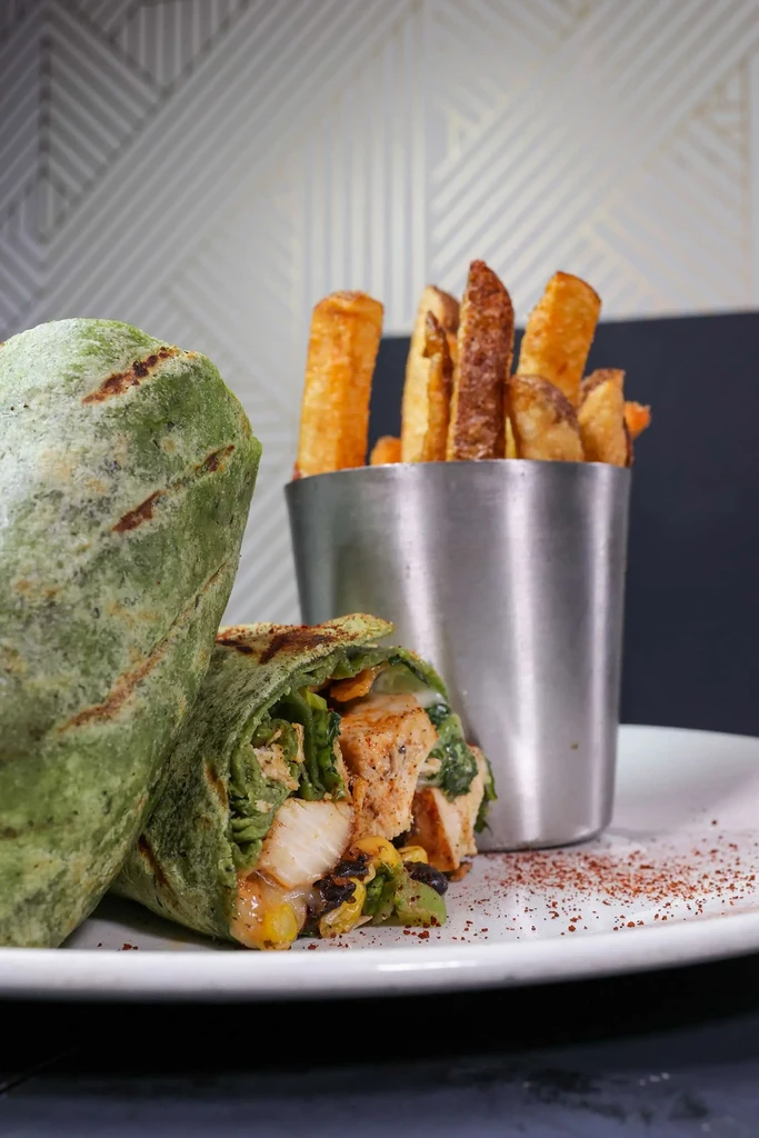 Green chicken wrap with corn and black beans, served with fries.