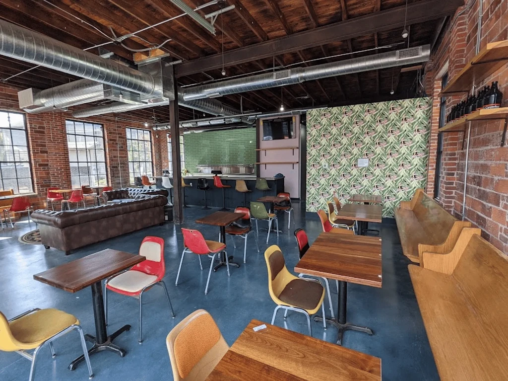 Industrial-chic restaurant interior with exposed brick, varied seating, and bar.