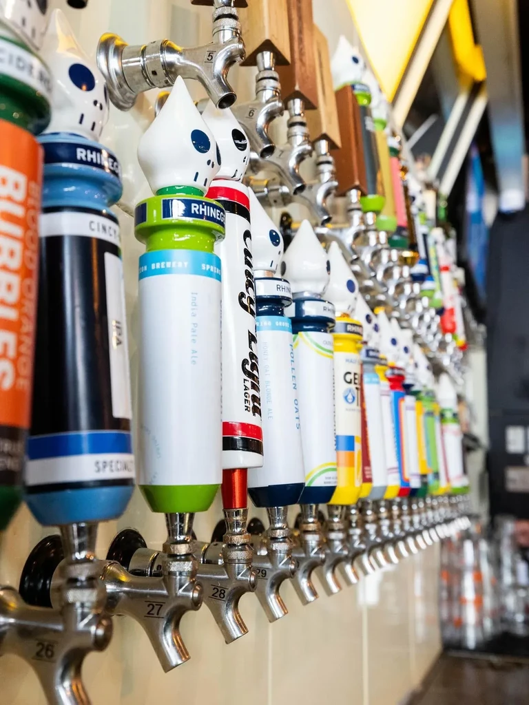 Long row of chrome beer taps with diverse, colorful handles.