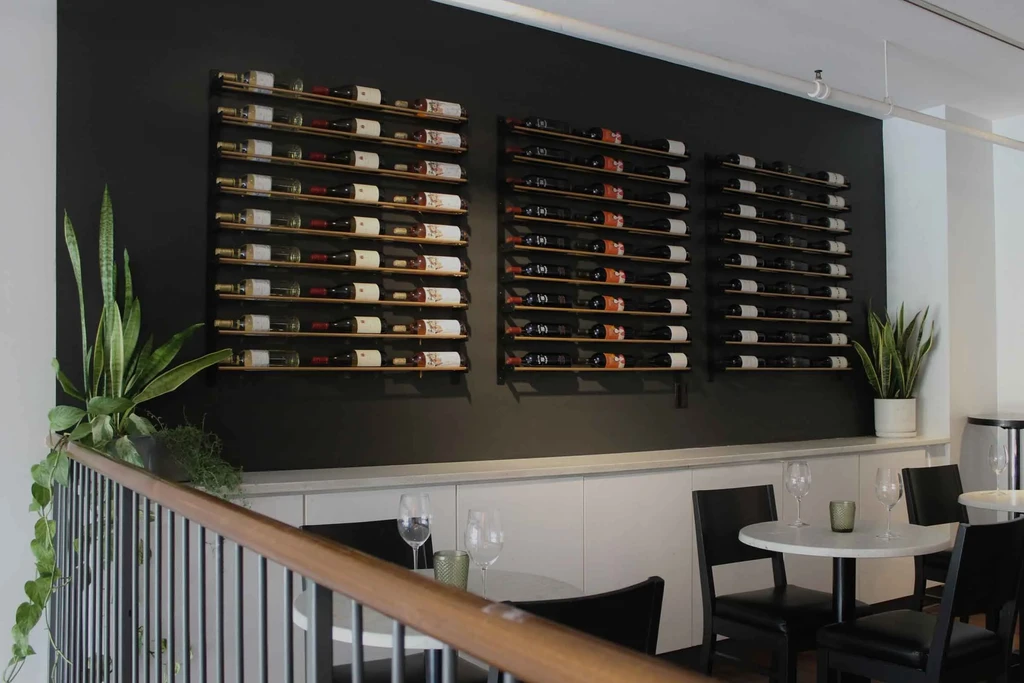 Modern restaurant interior with an expansive dark gray wine display wall.