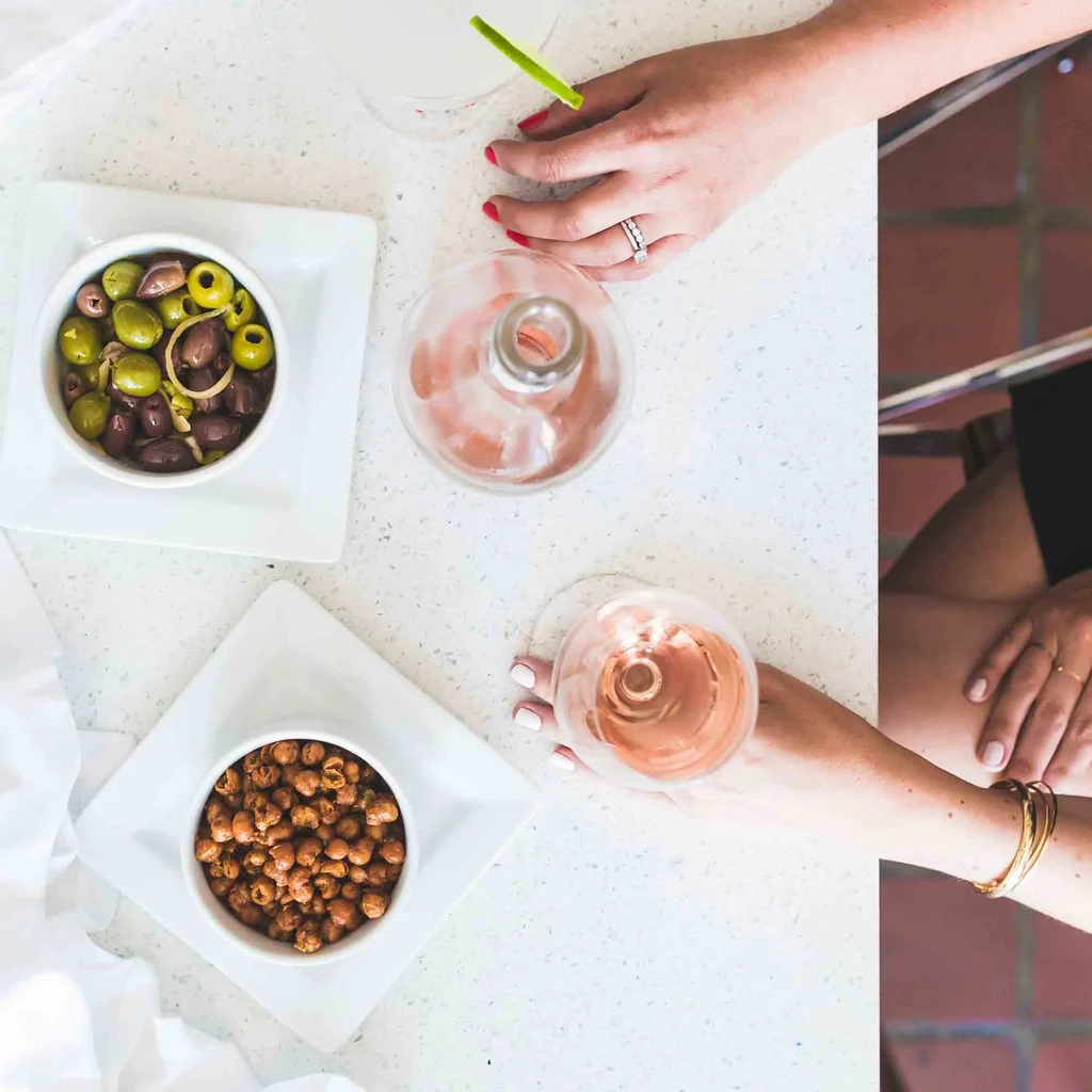 Overhead shot of olives, chickpeas, drinks, and hands on a table.