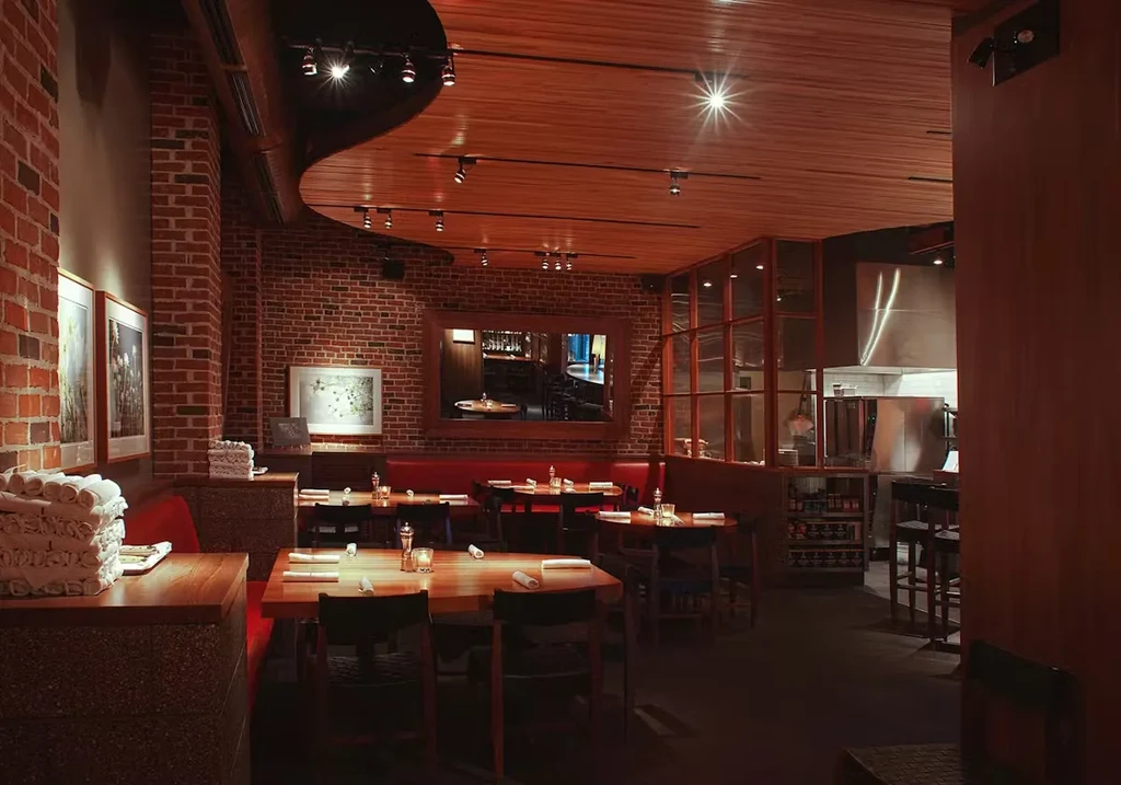 Warm restaurant interior with brick walls, red booths, and atmospheric lighting.