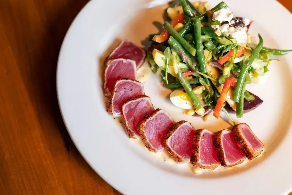 Rare seared tuna with colorful vegetable salad, feta, and egg.
