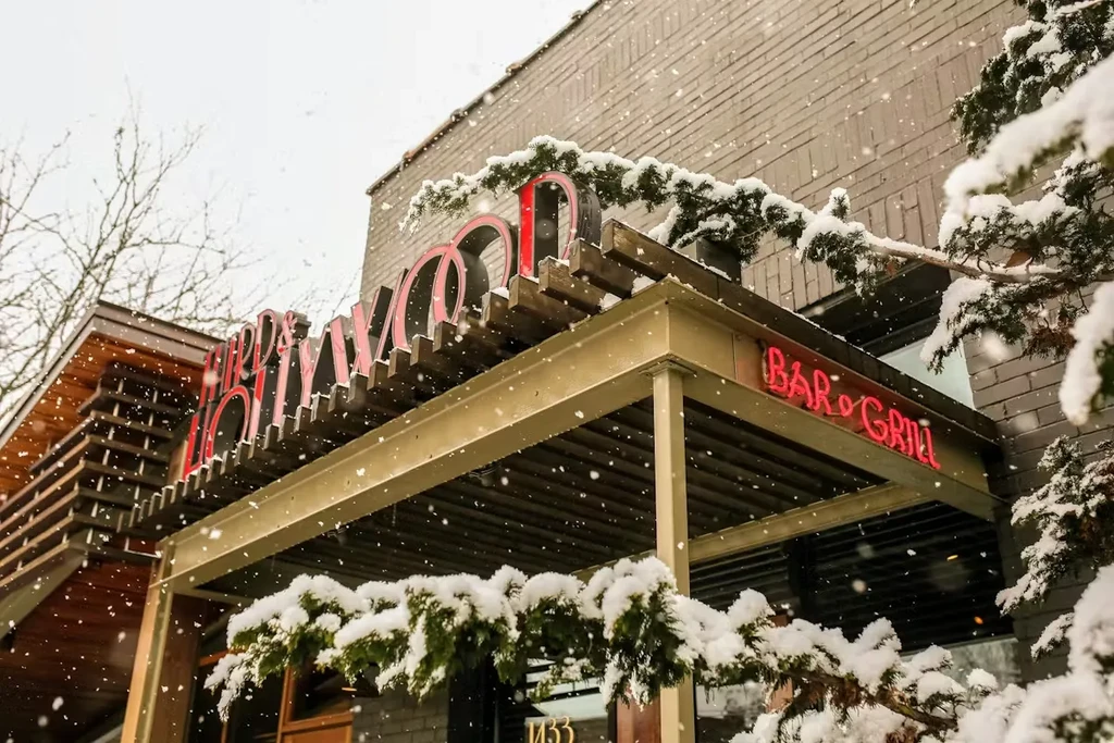 A snowy bar and grill entrance with glowing red neon signs.