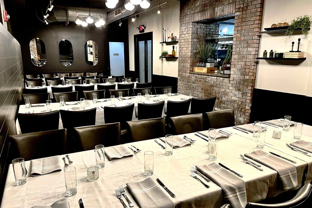Modern restaurant dining area with set tables, mirrors, and exposed brick.