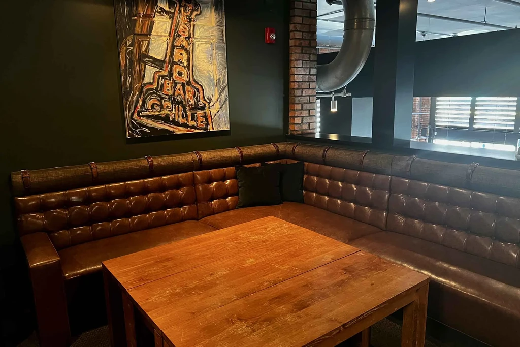 Tufted leather corner booth with dark table under "SEABOARD" artwork.